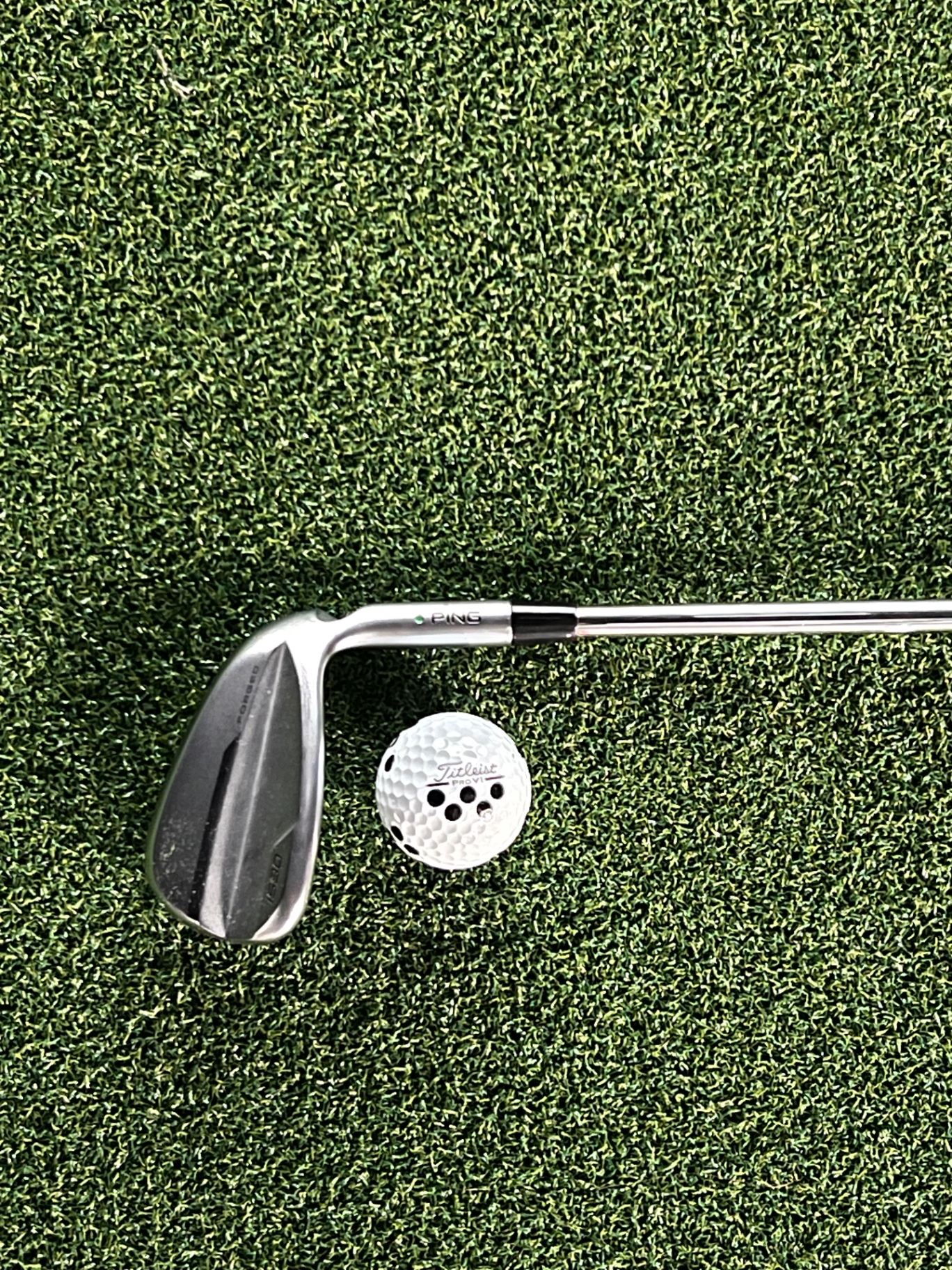 Forged wedge and a Titleist ball resting on the simulator turf