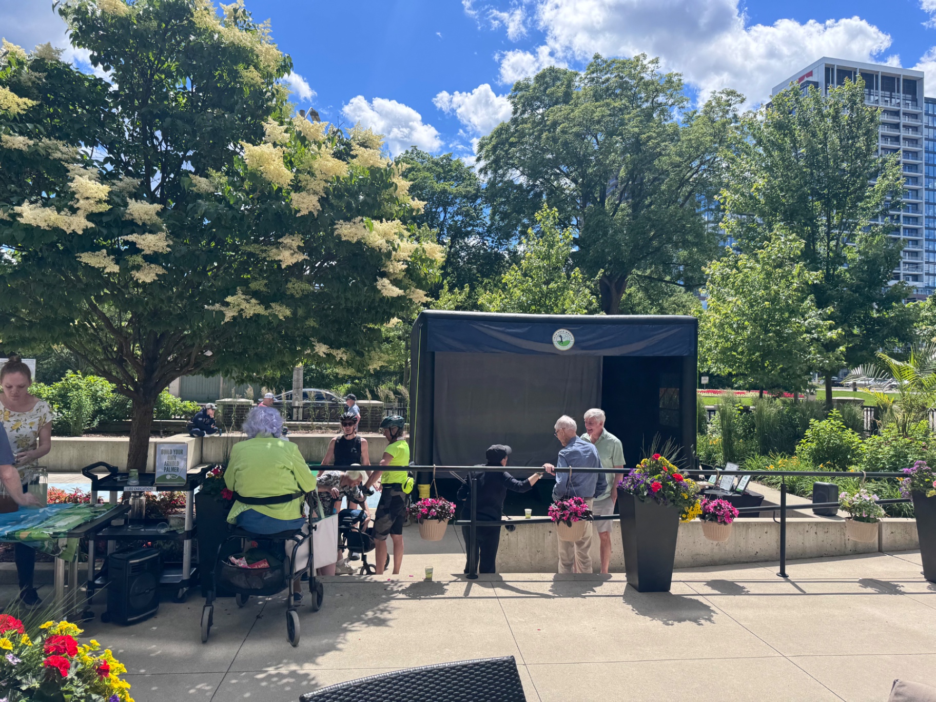 Guests gathered around the mobile golf simulator at an outdoor community plaza event