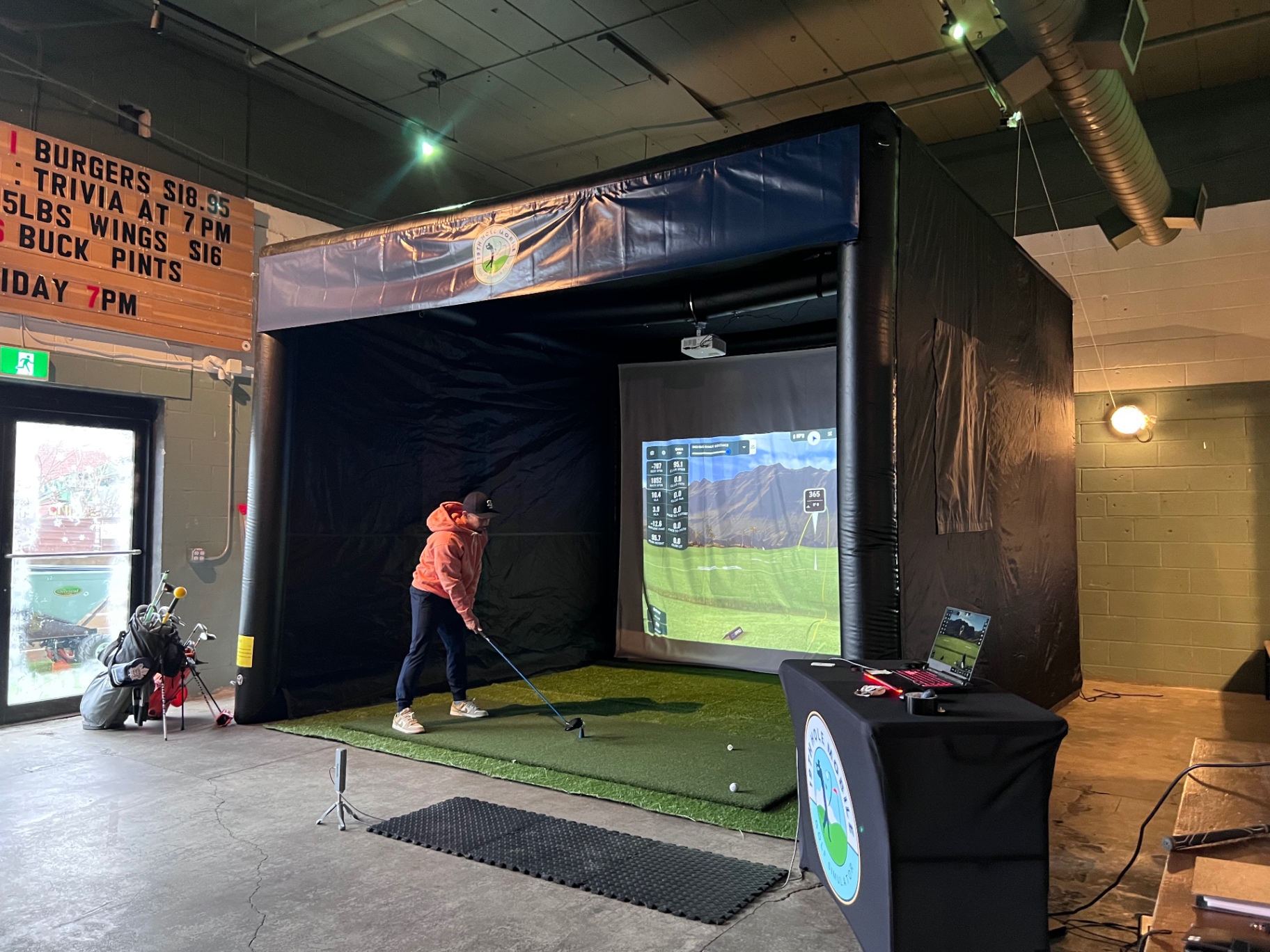 Guest driving a ball inside the mobile simulator at an indoor bar venue